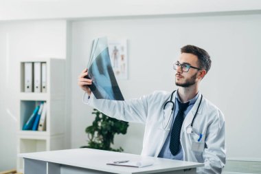 Doktor ofisinde röntgene bakıyor.