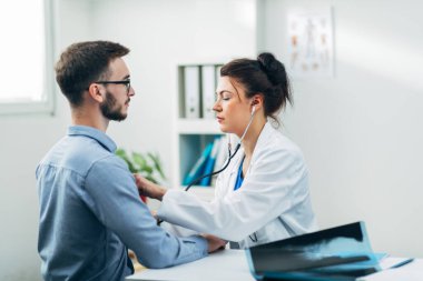 Doktor ve hasta doktorun ofisinde oturuyor.