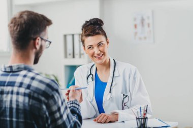 Doktor ve hasta doktorun ofisinde oturuyor.