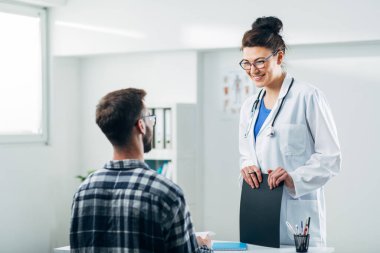 Doktor ve hasta doktorun ofisinde oturuyor.