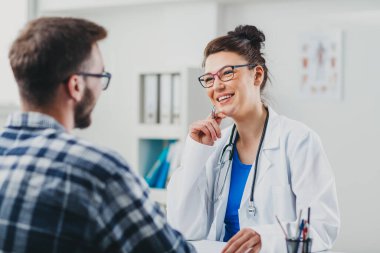 Doktor ve hasta doktorun ofisinde oturuyor.