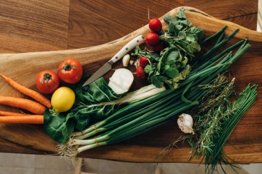 Mutfaktaki tahta kesme tahtasında çeşitli sebzeler var.