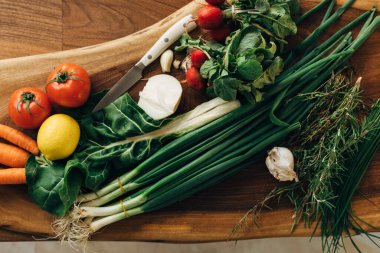 Mutfaktaki tahta kesme tahtasında çeşitli sebzeler var.