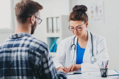 Doktor ve hasta doktorun ofisinde oturuyor.