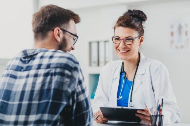 Doktor ve hasta doktorun ofisinde oturuyor.