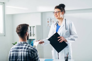 Doktor ve hasta doktorun ofisinde oturuyor.