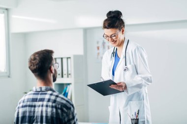 Doktor ve hasta doktorun ofisinde oturuyor.