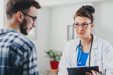 Doktor ve hasta doktorun ofisinde oturuyor.