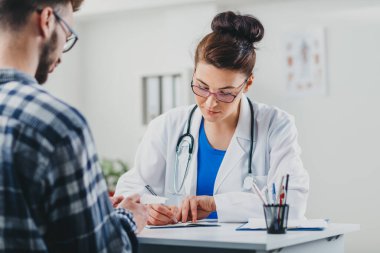 Doktor ve hasta doktorun ofisinde oturuyor.