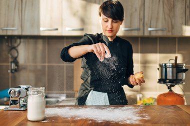 Kadın aşçı mutfakta hamur yoğuruyor.