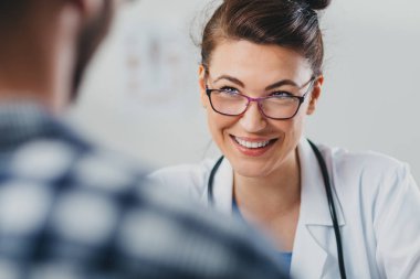 Doktor ve hasta doktorun ofisinde oturuyor.