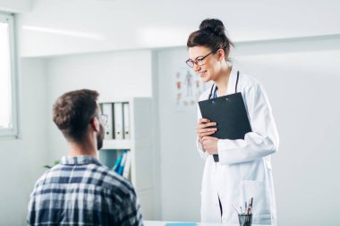 Doktor ve hasta doktorun ofisinde oturuyor.