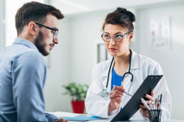 Doktor ve hasta doktorun ofisinde oturuyor.