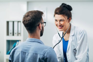 Doktor ve hasta doktorun ofisinde oturuyor.