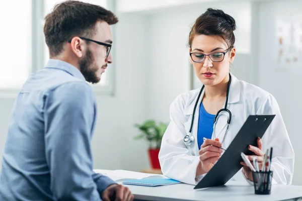 Doktor ve hasta doktorun ofisinde oturuyor.
