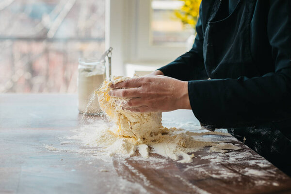 Female chef kneading dough in the kitchen