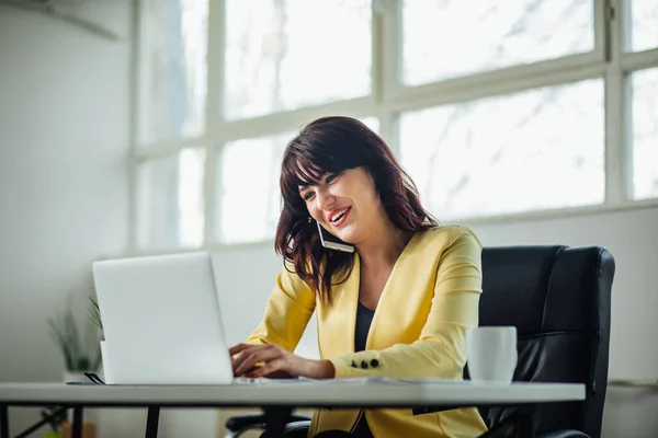 Young woman in office talking on a cell phone — Stockfoto