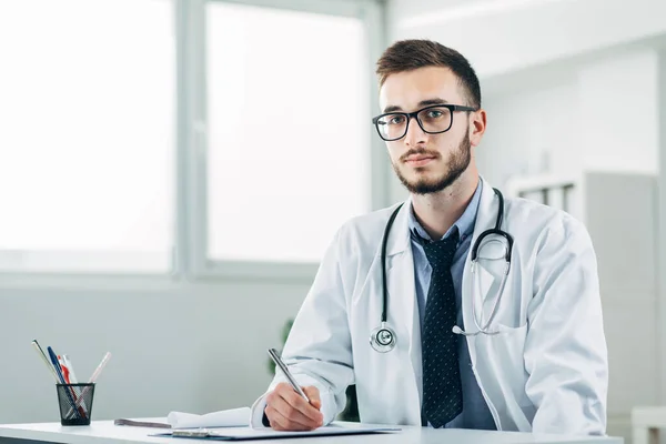 Jovem Médico Sentado Seu Escritório Atrás Uma Mesa — Fotografia de Stock