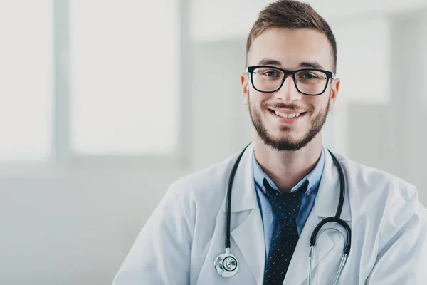 Genç doktor masasının arkasında ofisinde oturuyor.