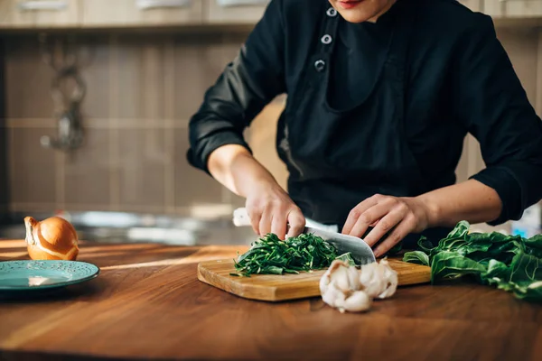 Female chef chopping raw vegetables on a wooden board — Stock Photo, Image