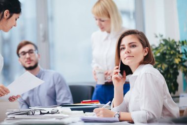 Ofiste iş arkadaşlarıyla çalışan bir kadın.