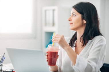 Ofiste Smoothie içen ve dışarı bakan çekici kadın.