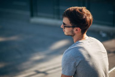 Gün batımında kaykay parkında oturan genç adam.