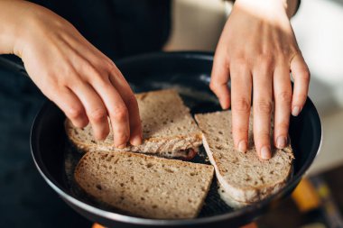 Şef tereyağlı tavada tam buğday ekmeği kızartıyor.