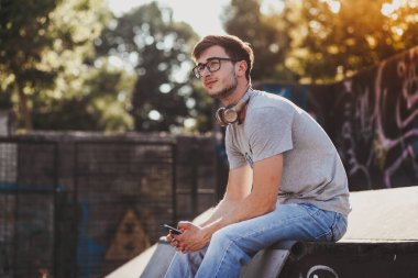 Gün batımında kaykay parkında oturan genç adam.