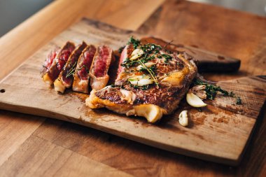 Dilimlenmiş sarımsaklı pirzola ve kekik tahta üzerinde dinleniyor.