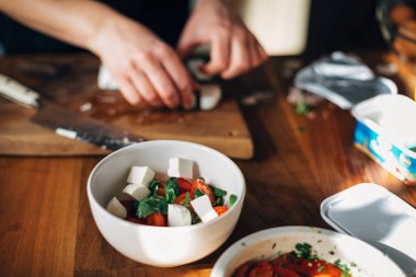 Kadın aşçı mutfakta Yunan salatası hazırlıyor.