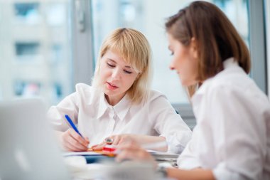 Ofiste iki kadın ara verip gülüyor.