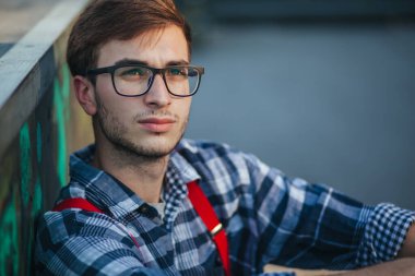 Gün batımında kaykay parkında oturan genç adam.