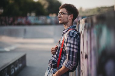 Gün batımında kaykay parkında duran genç adam.