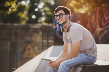 Gün batımında kaykay parkında oturan genç adam.