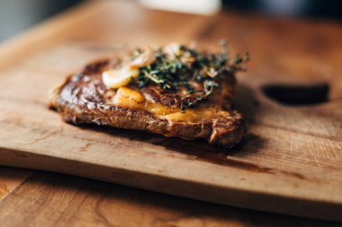 Restoran mutfağında tahta bir tahtanın üzerinde dinlenen pirzola bifteği.