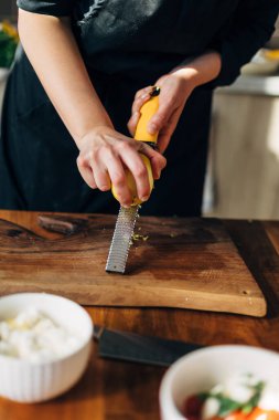Ahşap tahtada limon rendeleyen kadın şef.