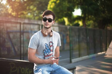 Gün batımında kaykay parkında oturan genç adam.