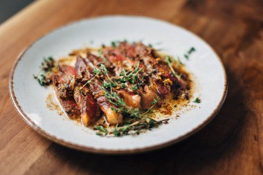 Bir tabakta servis edilen sarımsak ve kekik dilimlenmiş pirzola.