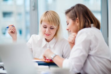 Ofiste iki kadın ara verip gülüyor.