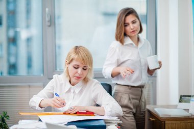 Ofiste iki kadın ara verip gülüyor.