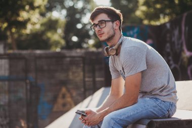 Gün batımında kaykay parkında oturan genç adam.