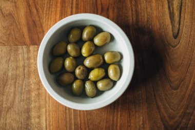 Tahta bir masada bir kase yeşil zeytin