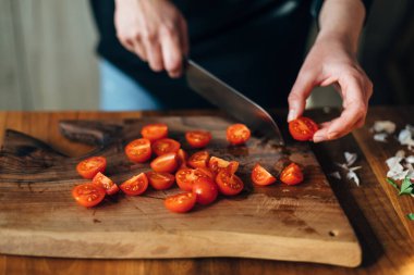 Ahşap bir tahtada bıçakla kiraz domateslerini doğrayan şef
