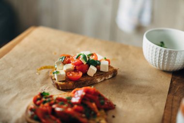 Tost ekmeğinde servis edilen fesleğen ve peynirli vişneli domates.