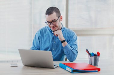 Ofisinde dizüstü bilgisayarda e-posta okuyan bir adam.