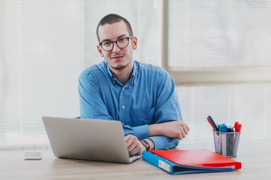 Ofisinde dizüstü bilgisayarda e-posta okuyan bir adam.