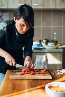 Ahşap bir tahtada bıçakla kiraz domateslerini doğrayan şef