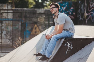 Gün batımında kaykay parkında oturan genç adam.