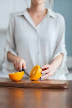 Mutfak tezgahında turuncu kesen güzel genç bir kadın.
